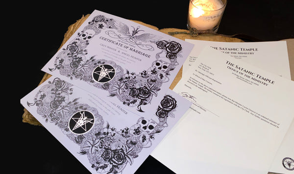 An arrangement that shows both letters and two certificates of marriage on a table with a candle and a book as visual context.