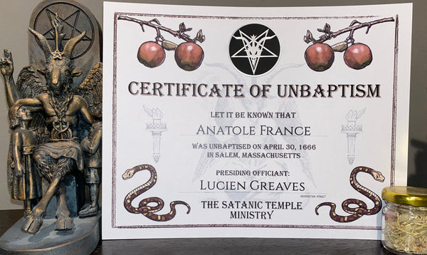 An arrangement that displays the Certificate of Unbaptism upright next to a small statue of Baphomet on the left and a small jar of loose incense on the right. The certificate is made out for Anatole France as the recipient with Lucien Greaves as the presiding officient.